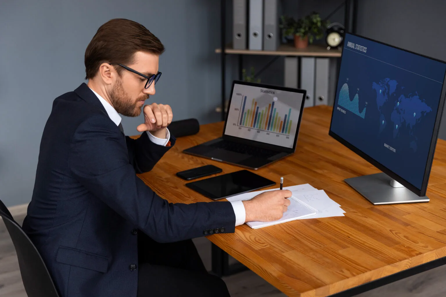 An office professional examining accounting data with audit charts displayed across two computer screens